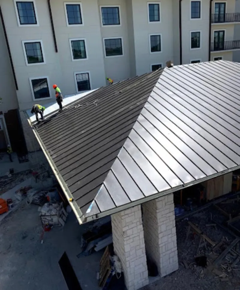 Crew installing standing seam metal roof panels on a commercial project in Shallotte